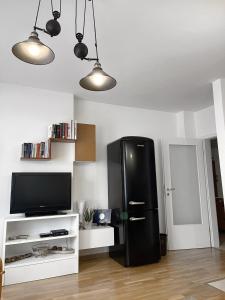 a black refrigerator in a living room with a tv at Pristina City Apartment in Pristina