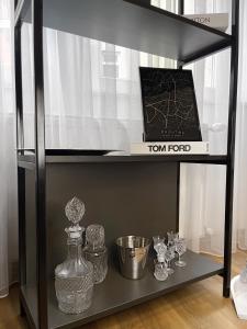 a black shelf with glass vases and a box at Pristina City Apartment in Pristina