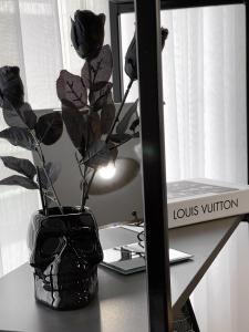 un vaso con fiori seduto su una scrivania accanto a uno specchio di Pristina City Apartment a Pristina