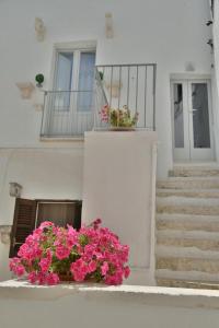 a white house with pink flowers and stairs at Casetta del vicolo orologio in Cisternino