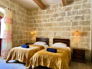 2 Betten in einem Zimmer mit einer Steinmauer in der Unterkunft Ta Lucija - Luxurious 6 Bedroom/En suite Villa - Pool / AC in Santa Luċija