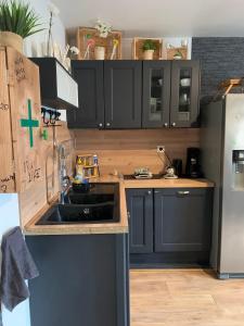 a kitchen with black cabinets and a sink and a refrigerator at Jojo House Les Damps n 12 in Les Damps
