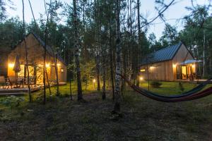 a hammock in front of a cabin in the woods at Ostoja Orżyny, Dom nr 1 - W stronę jeziora in Orzyny +14 photos