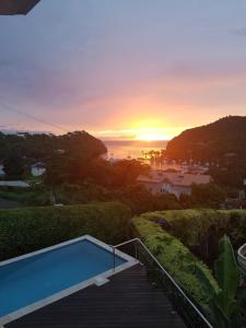 a swimming pool on a deck with a sunset in the background at Casa Vista in Marigot Bay