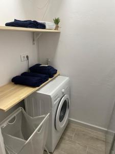 uma lavandaria com uma máquina de lavar roupa e toalhas azuis em Apartamento Tarifa Sunset em Tarifa