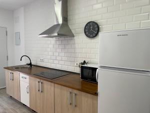 a kitchen with a refrigerator and a clock on the wall at Apartamento Tarifa Sunset in Tarifa