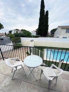 una mesa y 2 sillas en un balcón con vistas al océano en Magnifique villa avec piscine, en Villeneuve-lès-Maguelonne