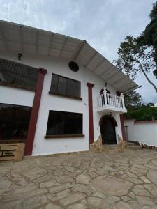 een wit huis met een veranda en een balkon bij Finca privada con excelente clima, rio natural, wifi y piscina in Cachipay