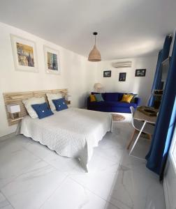 a white bedroom with a bed and a blue couch at Magnifique villa avec piscine in Villeneuve-lès-Maguelonne
