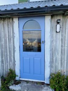 una puerta azul en un cobertizo con una ventana en Dave's Wee House en Kilcar