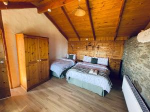 two beds in a room with wooden ceilings at Dave's Wee House in Kilcar