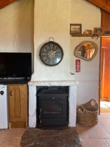 una chimenea en una cocina con un reloj en la pared en Dave's Wee House en Kilcar