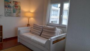 - un canapé blanc dans une chambre avec fenêtre dans l'établissement Carcavelos Surf Beach House, à Carcavelos