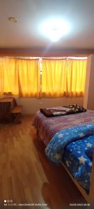 1 dormitorio con 2 camas y cortinas amarillas en Anacondor Tours & House en Cusco