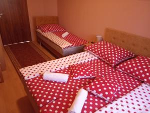 2 camas en una habitación con lunares rojos y blancos en Örségkapuja Vendégház, en Csákánydoroszló