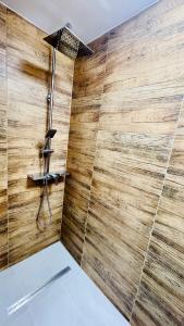 a shower in a bathroom with a wooden wall at Długa 100 in Charzykowy