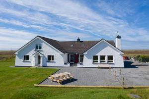 una casa blanca con una mesa de picnic delante de ella en Grianaig Guest House & Restaurant, South Uist, Outer Hebrides en Daliburgh