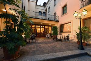 un patio con mesa y sillas en un edificio en Hotel Acqui & Centro Benessere en Acqui Terme