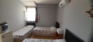 a small room with two beds and a television at Set Arat Motel & Pansiyon in Akçay