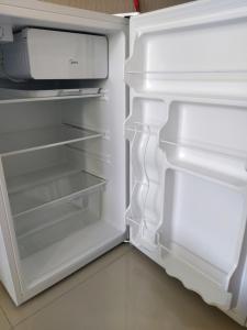 an empty refrigerator with its door open at Apart um dormitório com vista para estrada da rainha in Balneário Camboriú