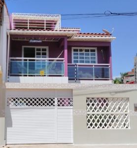 uma casa com um portão branco e um rosa em Aconchego em Maragogi