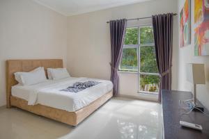 - une chambre avec un lit et une grande fenêtre dans l'établissement Villa Herrera Puncak, à Puncak