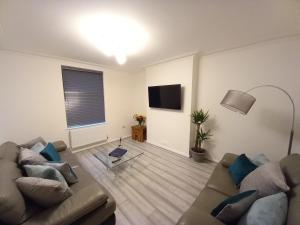 een woonkamer met 2 banken en een televisie bij Spacious & Modern 4 Bedroom Holiday Home Gwynedd in Bangor