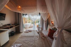Xamã Senses - Hotel Pousada في بيبا: غرفة نوم بسرير مع ستائر وحوض استحمام