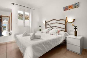 a white bedroom with a bed with white sheets and pillows at Apartamento Tramontana 113BJ in Fornells