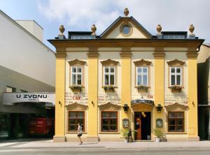 a woman walking in front of a yellow building at Hygge Hotel U Zvonu in Vrchlabí