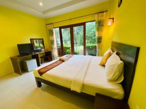 sypialnia z dużym łóżkiem z żółtymi ścianami w obiekcie Pranmanee Beach Resort w mieście Sam Roi Yot