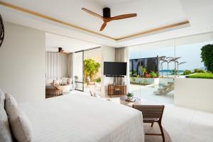een slaapkamer met een groot bed en een televisie bij Samujana Villas in Choeng Mon Beach