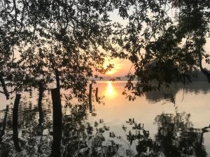 einen Sonnenuntergang über dem Wasser mit Bäumen im Vordergrund in der Unterkunft aji fruit farm in Embilipitiya