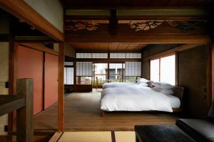 una camera da letto con un grande letto con lenzuola bianche di Umeyu no yado by YADORU KYOTO HANARE a Kyoto