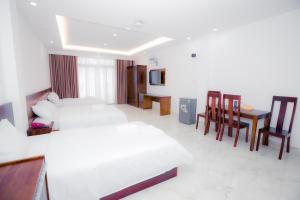 a hotel room with two beds and a table and chairs at Hồng Gấm Hotel in Quy Nhon
