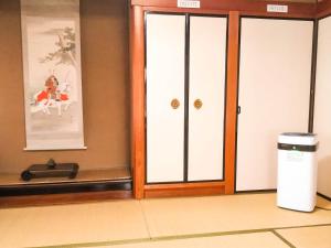 una puerta en una habitación con un cubo de basura en guest house AN en Otsu