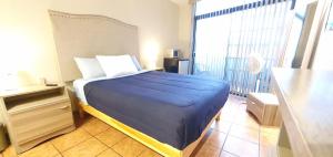 a bedroom with a blue bed with a large window at Hostal GGG in Ensenada