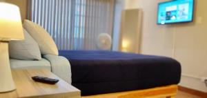 ein Schlafzimmer mit einem Bett und einer Fernbedienung auf dem Tisch in der Unterkunft Hostal GGG in Ensenada
