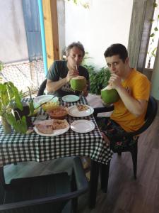dos hombres sentados en una mesa comiendo comida en Fuvahmulah inn, en Fuvahmulah