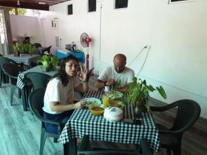 un hombre y una mujer sentados en una mesa en Fuvahmulah inn, en Fuvahmulah