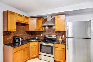 La cuisine est équipée d'armoires en bois et d'un réfrigérateur en acier inoxydable. dans l'établissement Spacious 1BD Apt in the heart of City, à Philadelphie