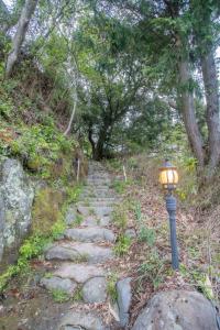 ゴンドラヴィラ イン熱海 في أتامي: ضوء الشارع بجوار مسار حجري به اشجار