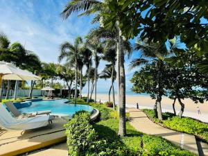 een zwembad naast een strand met palmbomen bij Baan Sanploen Hua Hin- Luxury Two Bedrooms in Hua Hin
