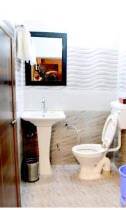 a bathroom with a white toilet and a sink at MH Guest House in Jodhpur