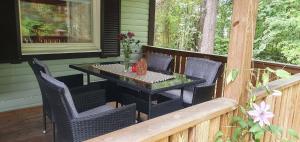 porche con mesa y sillas en la cubierta en Well-equipped Beachside Cottage, en Mönsterås