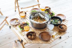 uma mesa cheia de comida e copos de sumo de laranja em 分校Stay haruhi グランピング em Ureshino