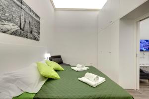 a bedroom with a bed with green and white pillows at Nise Duomo apartment in Florence