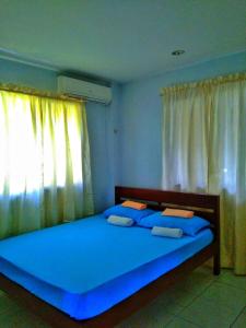 um quarto com uma grande cama azul e uma janela em D downhill'Place em Oslob