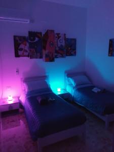 2 camas en una habitación con luces rosas y azules en All inBasilicata Bed & Breakfast, en Baragiano