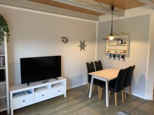 ein Esszimmer mit einem Tisch und einem Flachbild-TV in der Unterkunft Huus Utspann in Nordstrand